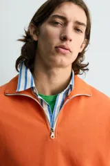 Sudadera regular fit azul marino confeccionada en tejido de algodón con estructura piqué. Cuenta con cuello subido, cierre frontal de cremallera corta y mangas largas con acabados en rib.