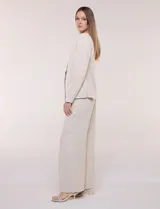 Blazer de sastrería color beige, sin solapas, con cuello en V profundo y cierre frontal de un único botón circular metálico en contraste.