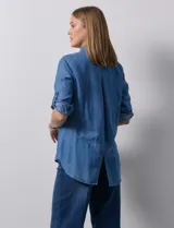 Camisa gris de tencel con cuello con solapa, escote en V y abertura central con botones. Largo de manga regulable con presilla y botón. Ruedo en espalda con tajo.