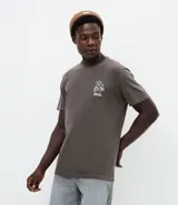 Remera de corte comfort color gris oscuro, con cuello redondo y mangas cortas. Presenta un pequeño estampado frontal con íconos étnicos y lettering en color blanco.