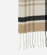 Bufanda de punto suave con estampado de cuadros en tonos beige, blanco y negro, con terminaciones de flecos en los extremos.