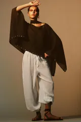 Capa negra de cuello redondo con detalle de tachas plateadas en el ruedo y pañuelo tipo bufanda integrado en el mismo tejido.