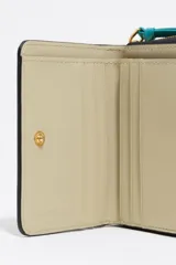 Billetera compacta de piel vacuna negra con estructura rígida, cierre de cremallera perimetral y tirador de tela en color turquesa. Incluye logo metálico dorado en el frente.