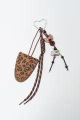 Llavero decorativo con estuche pequeño de cuero sintético con estampado animal print tipo leopardo, cordones marrones, mosquetón en forma de corazón y tira de dijes con cuentas, moño y dije con la inscripción "Dove".