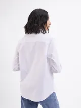 Camisa de corte clásico confeccionada en tela oxford color blanco, con cuello camisero, cierre frontal de botones, bolsillo aplicado en el pecho y puños abotonados.