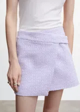 Minifalda cruzada de tweed color lavanda, con diseño asimétrico y detalle de solapa en la cintura. Confeccionada en mezcla de algodón, acrílico y poliamida, con forro de poliéster.