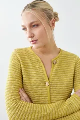 Chaqueta de punto color rojo, de corte entallado y manga larga. Presenta cuello redondo y cierre frontal con botones metálicos dorados texturizados.