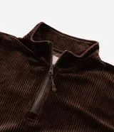 Campera deportiva de plush color marrón, con cuello alto, cierre frontal parcial y mangas largas con puños elásticos. Presenta una textura acanalada y un corte holgado.
