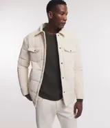 Campera puffer de terciopelo cotele color crema, con cuello inglés, manga larga, abotonado delantero y bolsillos de solapa en el pecho.