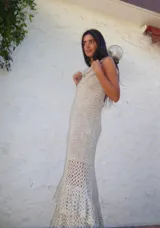 Vestido largo de crochet en color azul marino, con diseño sin mangas y cuello redondo. Presenta un detalle de apliques metálicos en la zona del pecho y un ruedo con volado de textura contrastante.