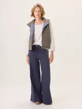 Chaleco con capucha, presenta una espalda de pelo sintético en color marrón oscuro con etiqueta de cuero negra y una capucha de tela tipo denim azul. Diseño original con mezcla de texturas.