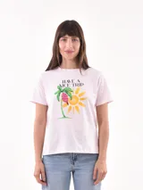 Remera rosa claro con estampado frontal de una palmera, un sol y la frase "HAVE A NICE TRIP".