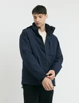 Campera 2 en 1 azul marino con capucha desmontable, cierre frontal con solapa de botones a presión y bolsillos laterales con cierre.