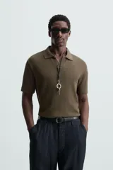Polo negro de manga corta con cuello solapa y abertura frontal. Presenta un tejido jacquard con textura geométrica sutil.