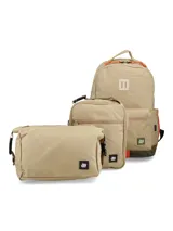 Kit compuesto por una mochila, una lonchera y una cartuchera, todos en color beige con detalles en naranja y verde oliva. La mochila cuenta con un compartimento principal con cierre, bolsillo frontal y parche de cuero. La lonchera y la cartuchera presentan un diseño rectangular con cierre y etiquetas de marca.