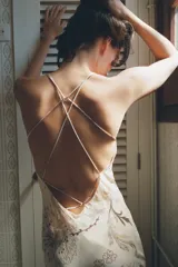Vestido midi de viscosa con estampado floral y geométrico en tonos neutros. Presenta escote redondo, tirantes finos cruzados en la espalda con ajuste de lazada y forro interior.