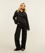 Pantalón de jean negro de tiro alto, corte estilo años 90 con perneras amplias y múltiples bolsillos cargo en los laterales. Cuenta con trabillas en la cintura y cierre frontal de botón y cremallera.