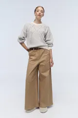 Pantalón de vestir color crema, de corte ancho y tiro alto. Se ajusta a la cintura con cinturón de cuero marrón.