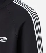 Campera deportiva de cuello alto con cierre frontal completo, mangas largas con rayas laterales blancas contrastantes y bolsillos laterales. Presenta un bordado pequeño en el pecho.