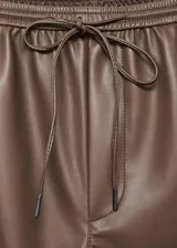 Pantalón efecto piel de color marrón, con diseño recto, tiro medio y cintura elástica con cordón ajustable. Cuenta con dos bolsillos laterales.