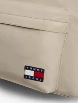 Mochila Tommy Jeans Essential Dome de tejido ripstop en color beige, con diseño curvo, compartimento principal con cierre de cremallera, bolsillo exterior frontal con cremallera, asa superior y correas ajustables y acolchadas. Incluye parche con el logo de la marca en el bolsillo frontal.