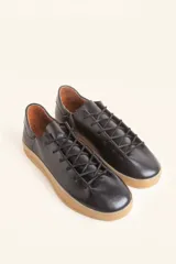 Zapatilla de cuero vacuno color azul marino, con cordones azules y suela de caucho color caramelo.