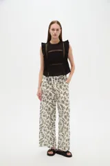 Blusa de algodón negra sin mangas, con cuello a la base, volados en los hombros y detalles de encaje y calados frontales.