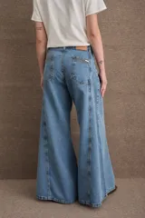 Jean de corte wide leg con tiro alto, confeccionado en denim azul oscuro. Presenta costuras verticales a lo largo de las piernas con pespuntes en color verde a contratono.