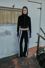 Pantalón de jogging negro de terciopelo con cintura elástica, corte recto y bandas laterales blancas.