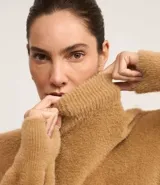Suéter de poliamida afelpada color tostado, con cuello alto y mangas largas de diseño holgado.