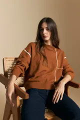 Sweater de punto color tierra con diseño de líneas blancas en contraste, cuello redondo, manga larga y puños tejidos.