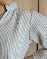 Blusa de algodón con cuello mao y volados, mangas largas con puños elásticos y corte holgado.