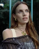 Collar con dije de forma irregular en tonos dorados y plateados, suspendido de un cordón doble de algodón negro.