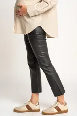 Pantalón negro de corte flare, tiro medio y efecto encerado.