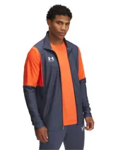 Campera deportiva Under Armour de la línea Challenger, con diseño de bloques de color en gris y naranja. Presenta cierre frontal completo, cuello alto y logo de la marca estampado en el pecho.
