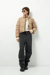 Campera puffer corta color beige de nylon, con cuello alto, cierre frontal y bolsillos laterales con cierre.