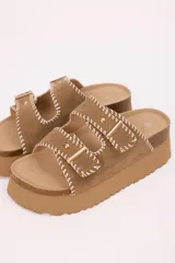 Sandalias con plataforma color marrón, doble tira en símil gamuza, costuras decorativas en blanco y hebillas metálicas doradas.