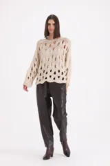 Sweater de punto color beige con diseño de calados circulares en toda la prenda, cuello redondo y mangas largas con puños acanalados.