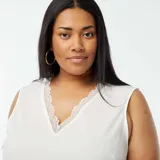 Blusa blanca sin mangas con cuello en V y borde de encaje.