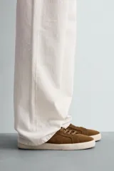 Zapatilla de cordones color verde militar, fabricada en piel con acabado serraje y suela plana color crema.