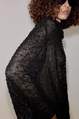 Camisa de hilatura con viscosa color negro, con cuello subido y manga larga ancha. Presenta aplicaciones de abalorios combinados a tono en toda la prenda y bajo recto.