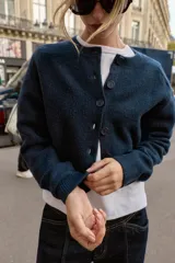 Chaqueta de punto de cuello redondo y manga larga, con cierre frontal de botones y acabados en rib.