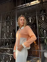 Chaqueta de punto color salmón con detalles en color crema en cuello, bolsillos y puños.