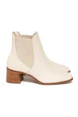Botines tipo Chelsea de cuero color off-white, con paneles laterales elásticos a tono, punta ligeramente cuadrada y tacón de bloque de madera.