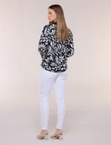 Blusa de calce suelto y caída ligera en color negro con estampado floral blanco, cuello camisero con escote en V y pechera en contraste. Presenta mangas tres cuartos abullonadas con puños elásticos.