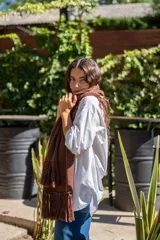 Bufanda tejida en color marrón con diseño de rombos en relieve y terminación con flecos en los extremos. Incluye una etiqueta de cuero sintético con la marca Diversa.