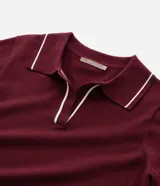 Suéter de punto en color bordó con corte slim, cuello polo y mangas largas. Presenta detalles de líneas blancas en contraste en el cuello y los puños, con acabado acanalado.