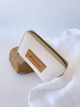 Billetera pequeña de cuero color crudo, con cierre metálico y monedero interno.