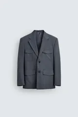 Blazer de corte regular confeccionada en tejido con lana, con cuello de solapas de muesca y manga larga con puños abotonados. Presenta cierre frontal de botonadura y cuatro bolsillos plastrón con solapa en el delantero.