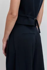 Pantalón de vestir de corte wide leg, color negro, con tiro alto y diseño de pinzas frontales. Presenta una caída fluida y holgada.